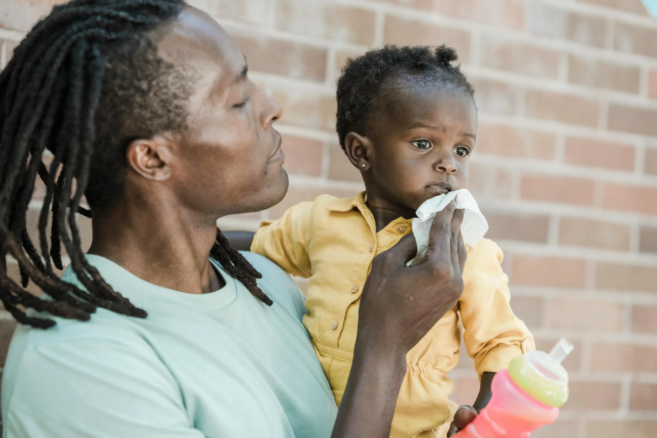 Dad wiping baby's mouth with body wipe